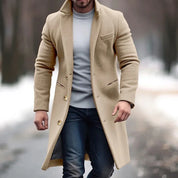 Uomo con cappotto beige elegante, maglione grigio e jeans, cammina su strada invernale. Moda maschile, abbigliamento invernale, stile casual.