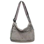 Borsa a tracolla in tela grigia, tasca frontale con zip, design casual, ideale per uso quotidiano. Accessorio moda pratico e versatile.