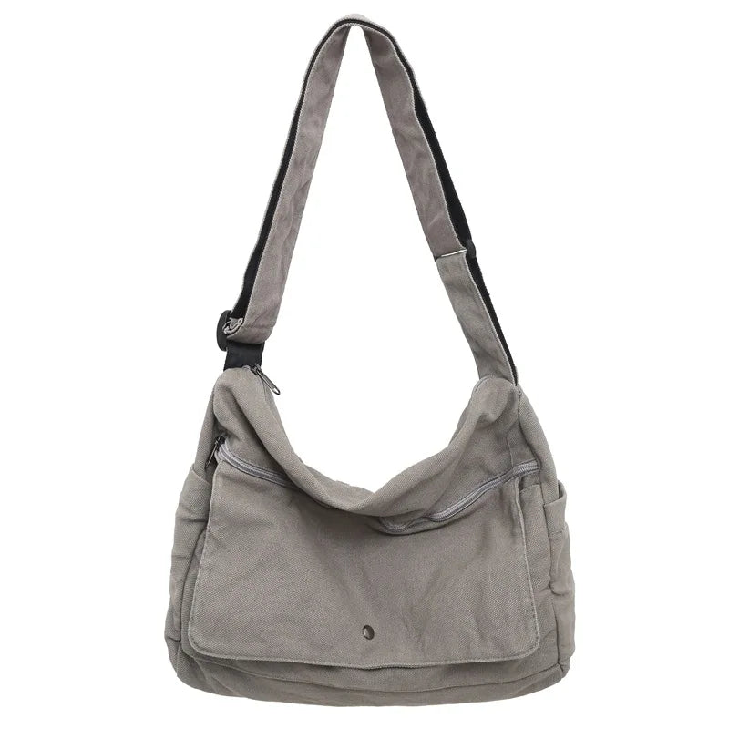 Borsa a tracolla in tela grigia, tasca frontale con zip, design casual, ideale per uso quotidiano. Accessorio moda pratico e versatile.