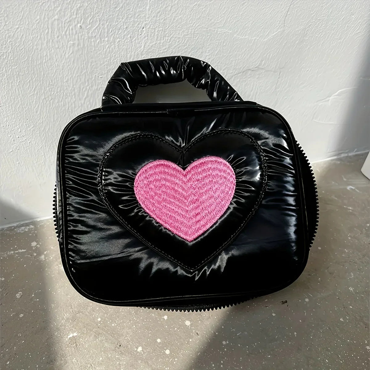 Borsa a mano nera in pelle lucida con cuore rosa al centro, design moderno ed elegante, accessorio moda donna, perfetta per ogni occasione.
