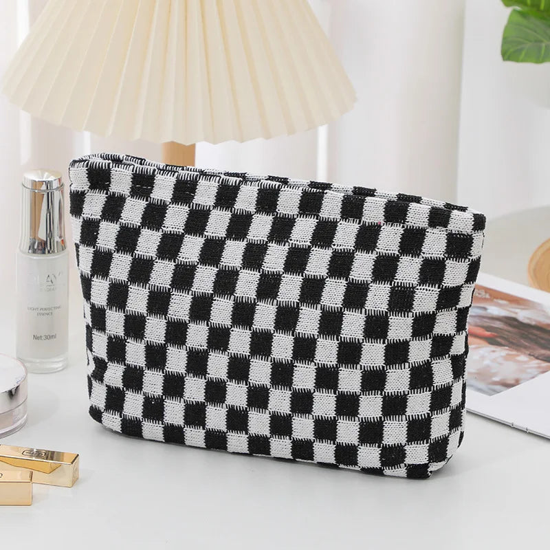 Borsa a scacchi bianca e nera su tavolo, design moderno, ideale per cosmetici. Accessorio moda elegante, perfetto per organizzare trucchi.
