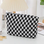 Borsa a scacchi bianca e nera su tavolo, design moderno, ideale per cosmetici. Accessorio moda elegante, perfetto per organizzare trucchi.