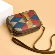 Borsa a tracolla multicolore in pelle con motivo geometrico, chiusura a zip e tracolla regolabile, su sfondo beige. Accessorio moda elegante.