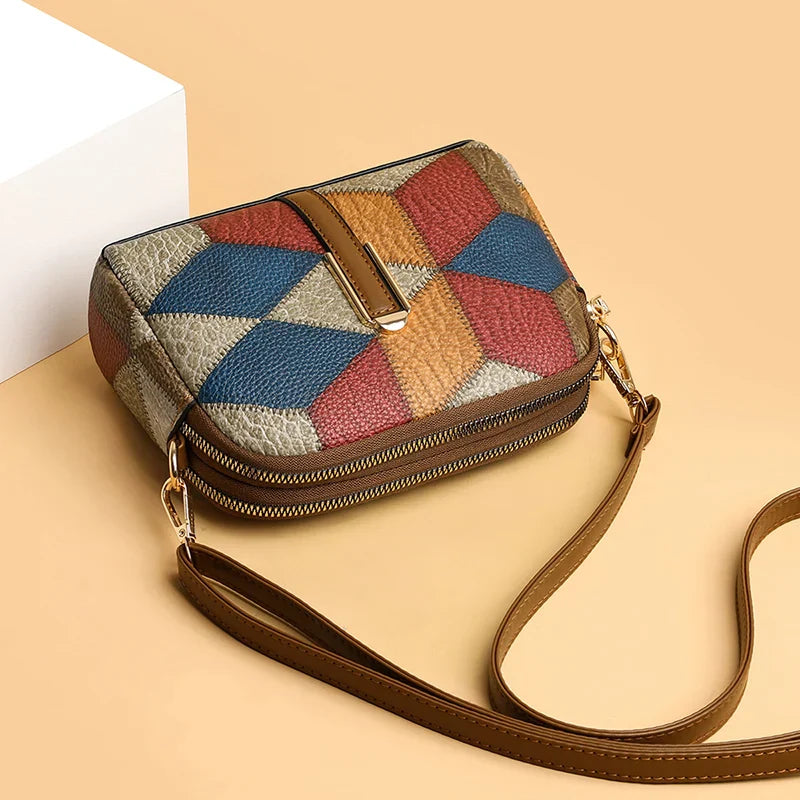 Borsa a tracolla multicolore in pelle con motivo geometrico, chiusura a zip e tracolla regolabile, su sfondo beige. Accessorio moda elegante.