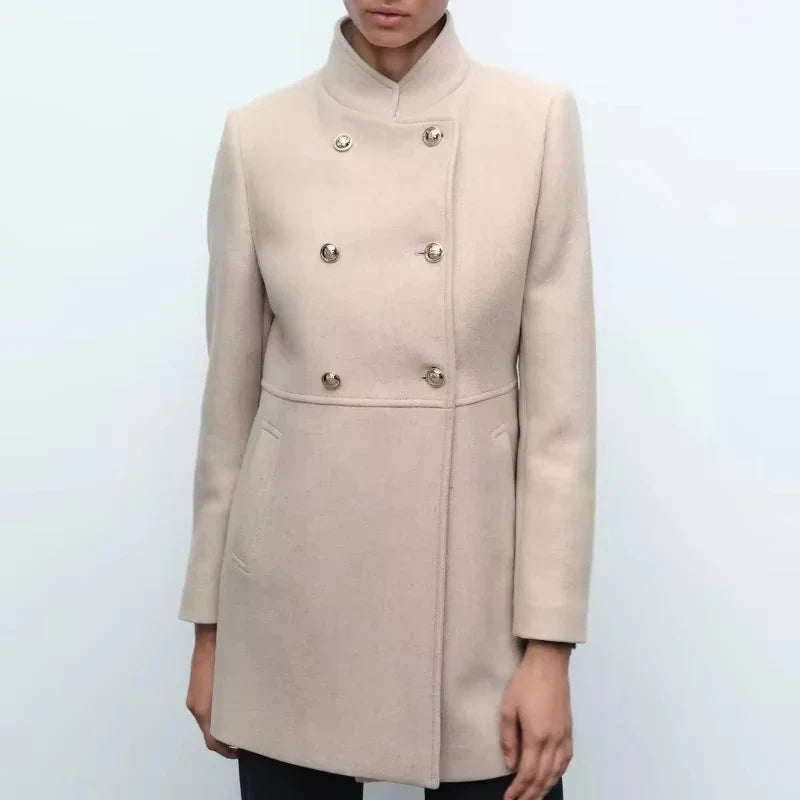 Cappotto donna beige elegante, doppio petto, bottoni dorati, collo alto, tasche laterali. Moda autunno inverno, abbigliamento femminile chic.