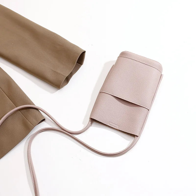 Borsa a tracolla in pelle rosa chiaro su sfondo bianco, design minimalista, ideale per smartphone. Accessorio moda elegante e pratico.