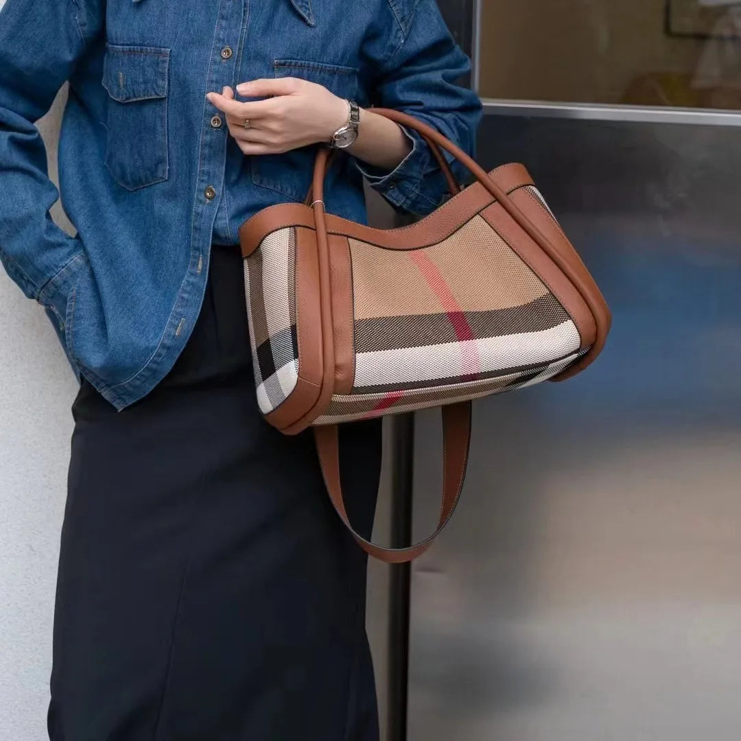 Donna con borsa a tracolla in tessuto a quadri beige e marrone, dettagli in pelle marrone, indossa camicia di jeans e gonna nera. Accessorio moda elegante.