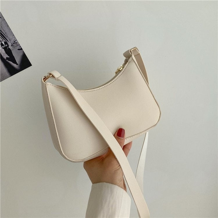 Borsa a tracolla bianca minimalista, design elegante, in pelle sintetica, tenuta in mano. Accessorio moda donna, stile casual chic.