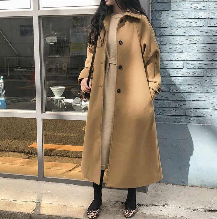 Cappotto lungo beige donna, elegante e moderno, indossato su abito chiaro. Moda autunnale, stile casual chic, perfetto per giornate fresche.