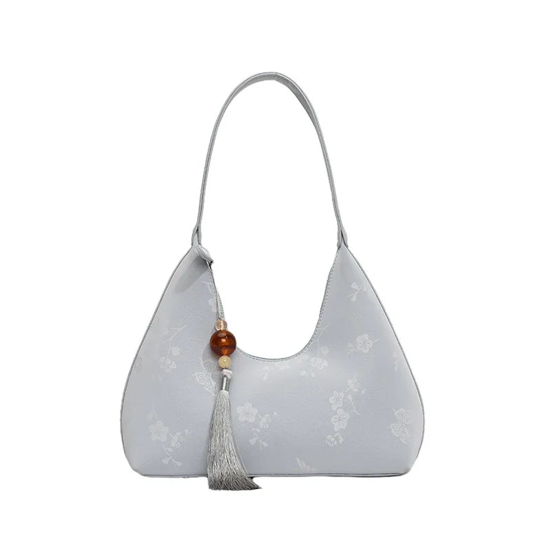 Borsa a spalla grigia in pelle con motivo floreale, decorata con nappina e perla. Elegante accessorio moda donna, ideale per ogni occasione.