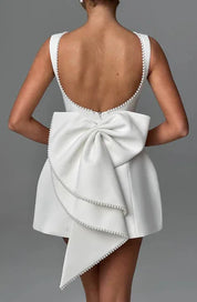 Abito bianco elegante con schiena scoperta e grande fiocco posteriore, decorato con perline. Perfetto per cerimonie e occasioni speciali.