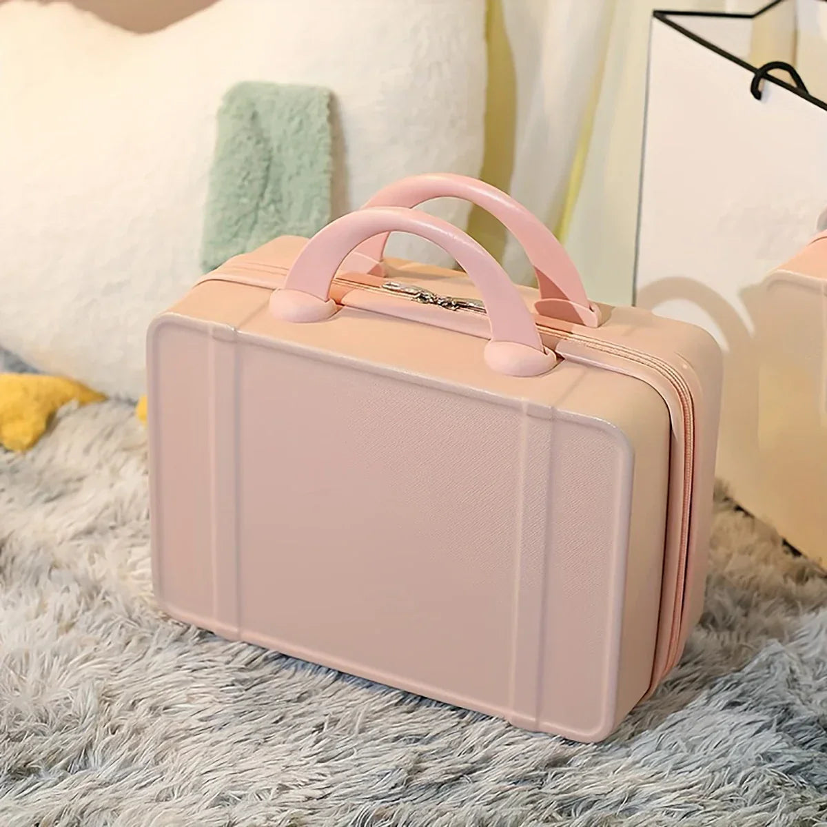 Valigia rosa compatta su tappeto grigio, design elegante, manico doppio, ideale per viaggi brevi. Accessorio moda, pratico e leggero.