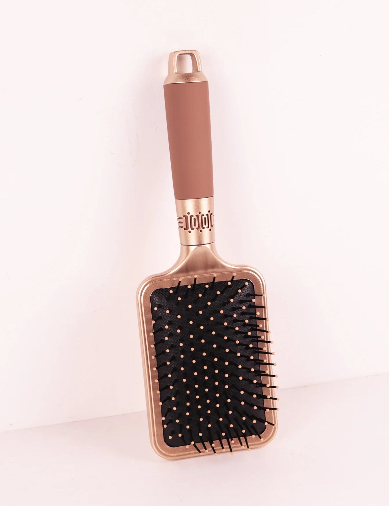 Spazzola per capelli rettangolare dorata con setole nere e manico ergonomico marrone, ideale per districare e lisciare i capelli.