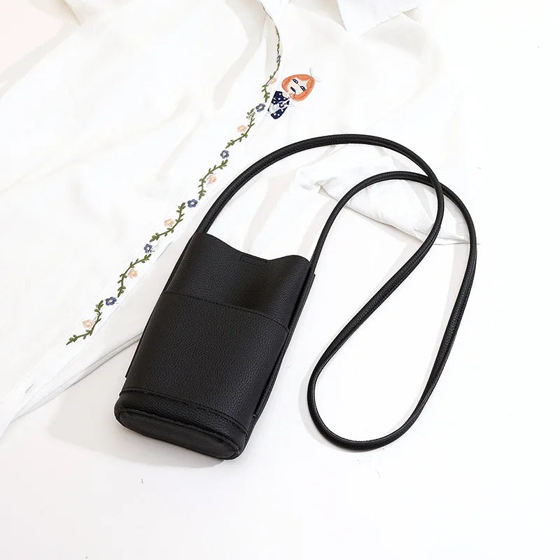 Borsa a tracolla nera in pelle sintetica su camicia bianca ricamata, design minimalista, ideale per moda casual e accessori donna eleganti.