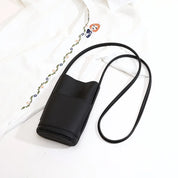 Borsa a tracolla nera in pelle sintetica su camicia bianca ricamata, design minimalista, ideale per moda casual e accessori donna eleganti.