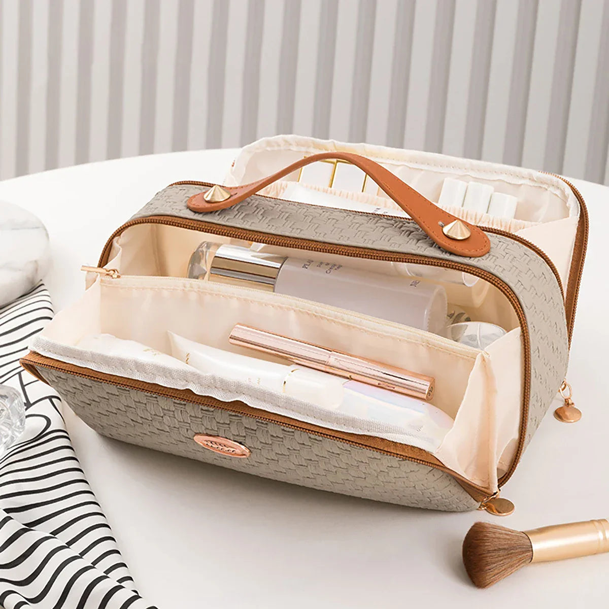 Borsa da trucco beige con manico in pelle, scomparti multipli e cerniera, ideale per organizzare cosmetici e accessori da viaggio.