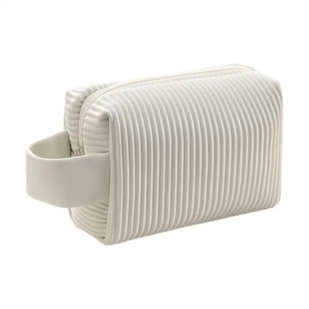 Astuccio da viaggio bianco in pelle con design a coste, manico laterale. Elegante e pratico per cosmetici o accessori.