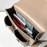 Borsa a tracolla beige aperta, con libri e accessori all'interno. Design elegante, ideale per lavoro e scuola. Tasche multiple per organizzazione.