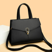 Borsa a mano donna in pelle nera, elegante e moderna, con tracolla regolabile e chiusura a fibbia dorata, su sfondo beige. Accessorio moda.