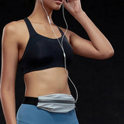 Donna in abbigliamento sportivo nero e blu, con marsupio grigio e auricolari, su sfondo nero. Fitness, accessori sportivi, moda attiva.