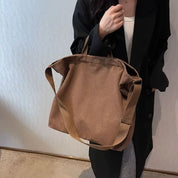 Borsa a tracolla marrone in tessuto, indossata da una persona con cappotto nero. Design casual, ideale per moda autunnale e invernale.