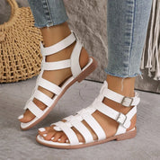 Sandali gladiatore bianchi da donna, con cinturini multipli e fibbie, indossati con jeans. Scarpe estive eleganti e comode per look casual.