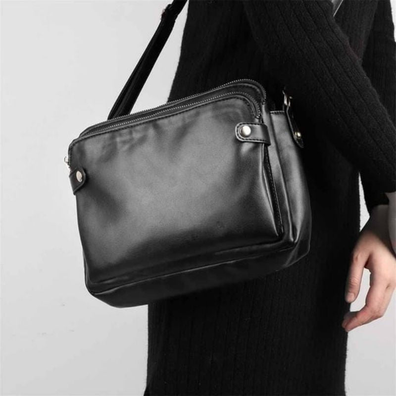 Borsa a tracolla in pelle nera, design elegante e minimalista, chiusura con zip, ideale per uomo, moda casual, accessorio versatile e resistente.