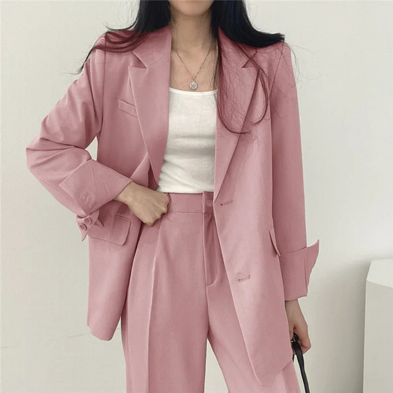 Donna in abito elegante rosa, giacca e pantaloni coordinati, indossa una maglietta bianca. Moda femminile, abbigliamento formale, tendenze 2023.