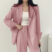 Donna in abito elegante rosa, giacca e pantaloni coordinati, indossa una maglietta bianca. Moda femminile, abbigliamento formale, tendenze 2023.