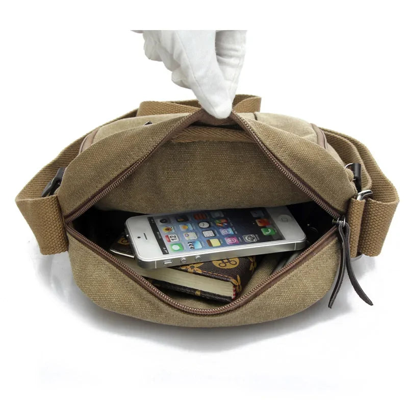Borsa a tracolla in tela beige aperta, mostra smartphone, portafoglio e libro. Design casual, ideale per uomo e donna. Accessori moda pratici.