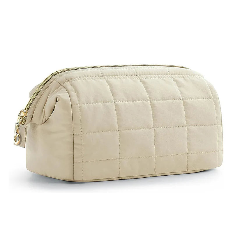 Borsa da toilette trapuntata beige con cerniera dorata, design elegante e spazioso, ideale per viaggi e organizzazione cosmetici.