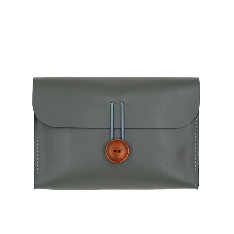 Portafoglio in pelle grigia con chiusura a bottone in legno, design elegante e minimalista, accessorio moda uomo e donna, alta qualità artigianale.