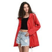 Giacca impermeabile rossa da donna, con cappuccio e tasche, indossata su top nero e shorts di jeans. Moda casual, abbigliamento outdoor.