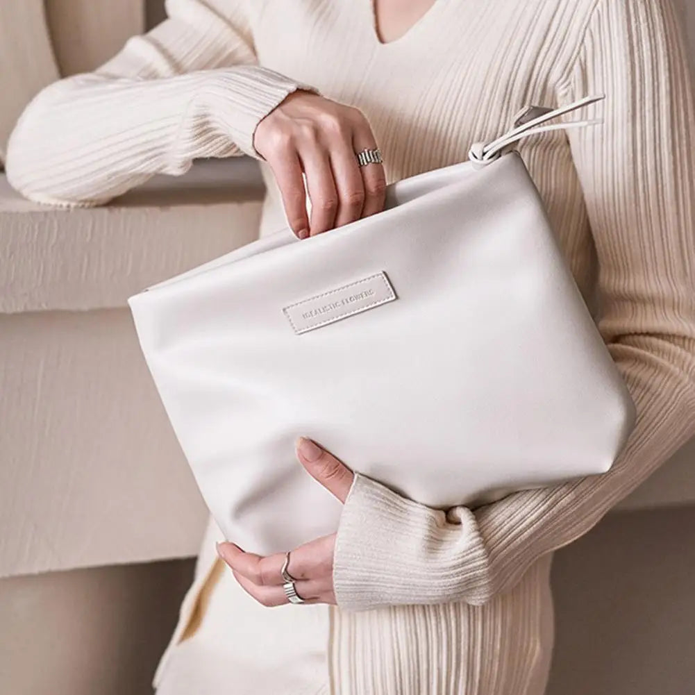 Donna con maglione beige tiene una borsa clutch bianca in pelle, elegante e minimalista, ideale per moda autunnale. Accessorio di tendenza.