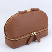Borsa cosmetica in pelle marrone con doppia cerniera dorata, design elegante e compatto, ideale per organizzare trucchi e accessori da viaggio.