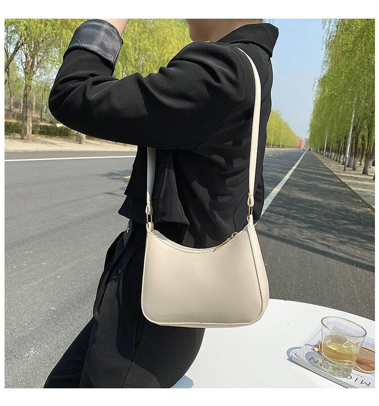 Donna con borsa a tracolla beige su strada alberata. Moda femminile, accessori eleganti, stile casual chic. Perfetta per shopping e uscite quotidiane.