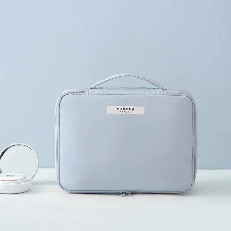Borsa trucco grigia con manico, design elegante e compatto, ideale per organizzare cosmetici. Perfetta per viaggi e uso quotidiano.