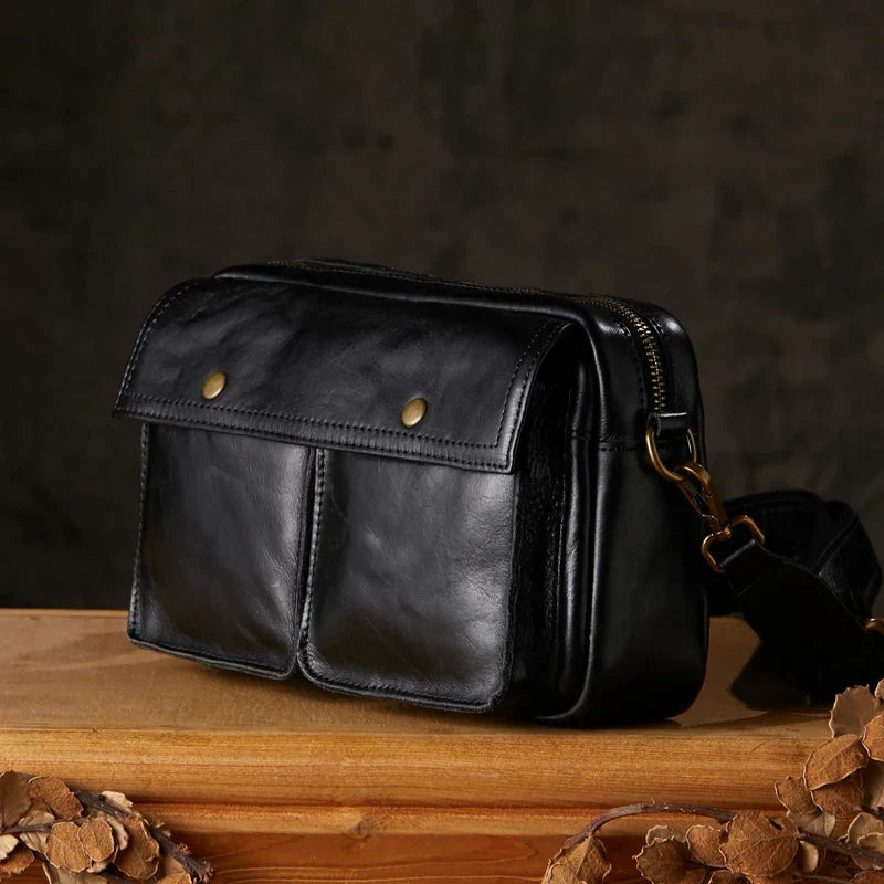 Borsa a tracolla in pelle nera con doppie tasche frontali e chiusura a zip, design elegante e pratico, ideale per uomo e donna.