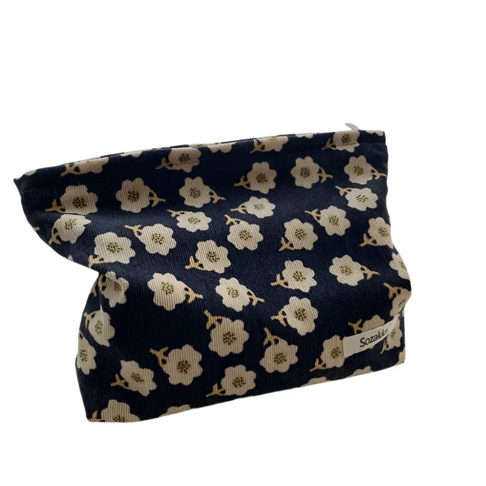 Borsa cosmetica floreale blu con fiori bianchi, design elegante, ideale per trucco e accessori, perfetta per viaggi e uso quotidiano.