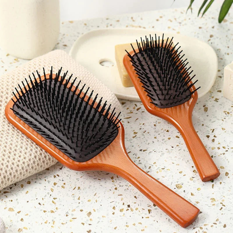 Spazzola per capelli in legno con setole nere su sfondo chiaro, ideale per districare e lisciare. Accessorio essenziale per la cura dei capelli.