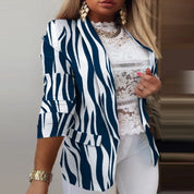Giacca a righe zebrate blu e bianche, maniche a tre quarti, indossata su top in pizzo bianco. Look elegante e moderno per donna.