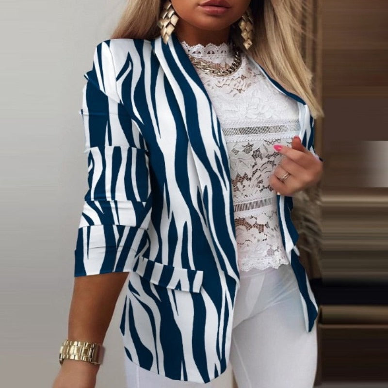 Giacca a righe zebrate blu e bianche, maniche a tre quarti, indossata su top in pizzo bianco. Look elegante e moderno per donna.