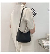 Donna in abito bianco con borsa a tracolla nera minimalista, design elegante, moda femminile, accessorio chic, stile moderno.