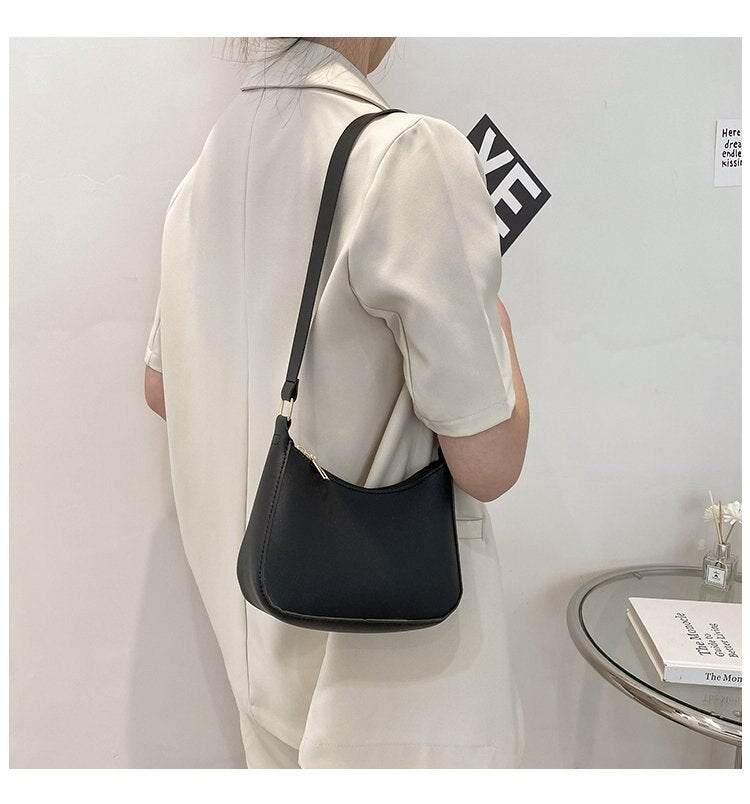 Donna in abito bianco con borsa a tracolla nera minimalista, design elegante, moda femminile, accessorio chic, stile moderno.