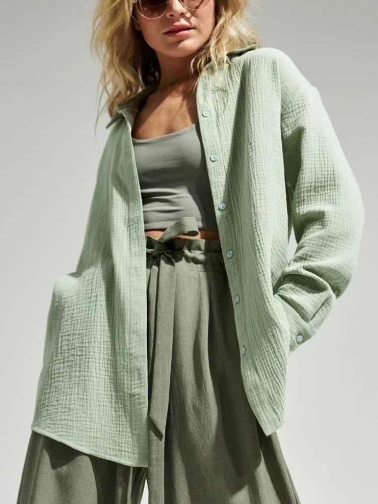 Donna con camicia verde chiaro in cotone, top e pantaloni coordinati, occhiali da sole. Moda estiva casual, abbigliamento femminile trendy.