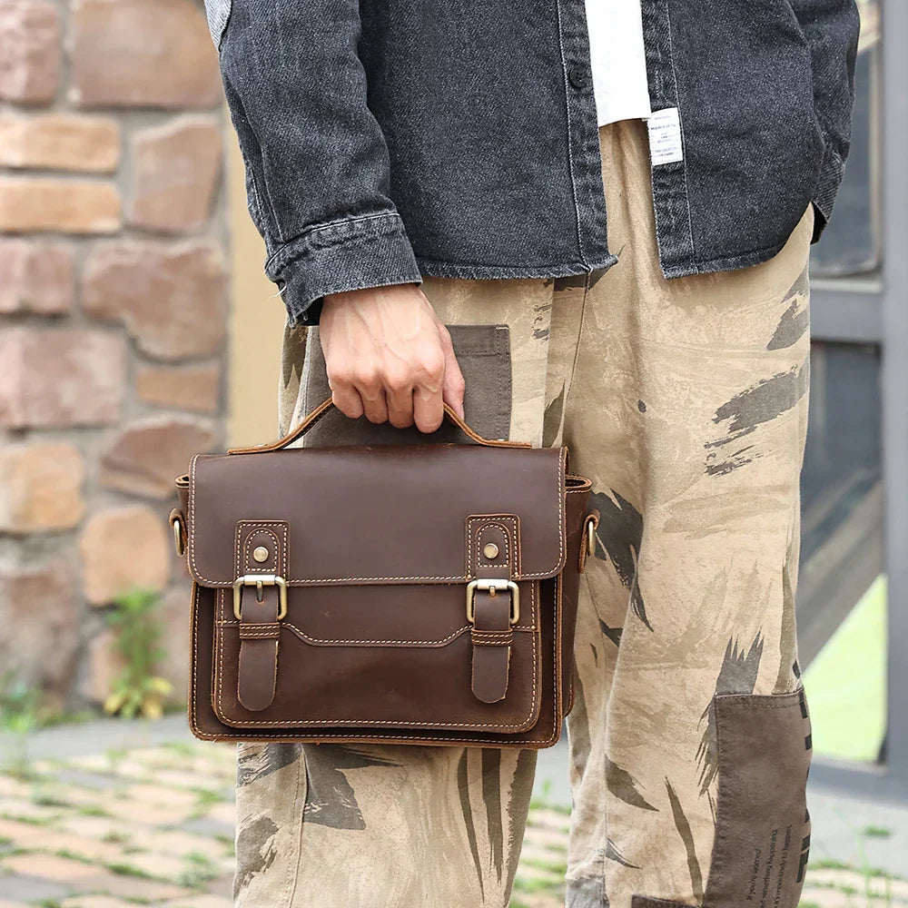 Borsa a tracolla in pelle marrone, stile vintage, con fibbie, indossata da uomo in jeans e pantaloni casual. Accessorio moda maschile elegante.