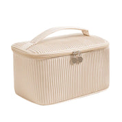 Borsa cosmetica beige con cerniera, design a coste, manico superiore. Ideale per trucco e accessori da viaggio. Elegante e funzionale.