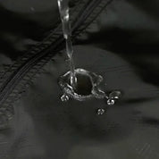 Flusso d'acqua su tessuto impermeabile nero con cerniera, dimostrando resistenza all'acqua. Ideale per abbigliamento outdoor e attrezzature sportive.