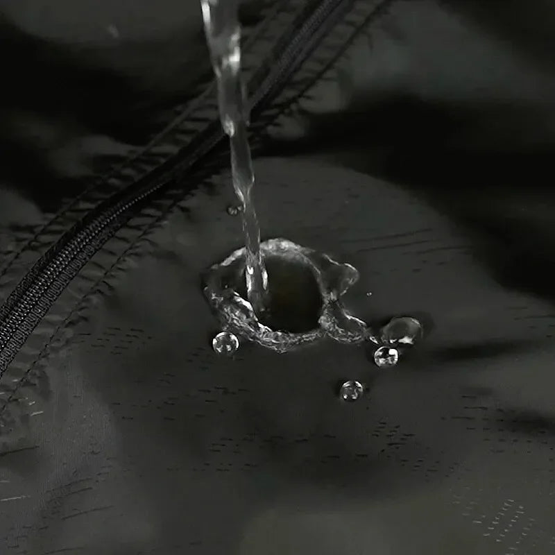 Flusso d'acqua su tessuto impermeabile nero con cerniera, dimostrando resistenza all'acqua. Ideale per abbigliamento outdoor e attrezzature sportive.