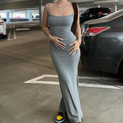 Abito lungo grigio aderente indossato da donna in parcheggio, stile casual elegante, perfetto per eventi serali. Scarpe da ginnastica gialle e nere.